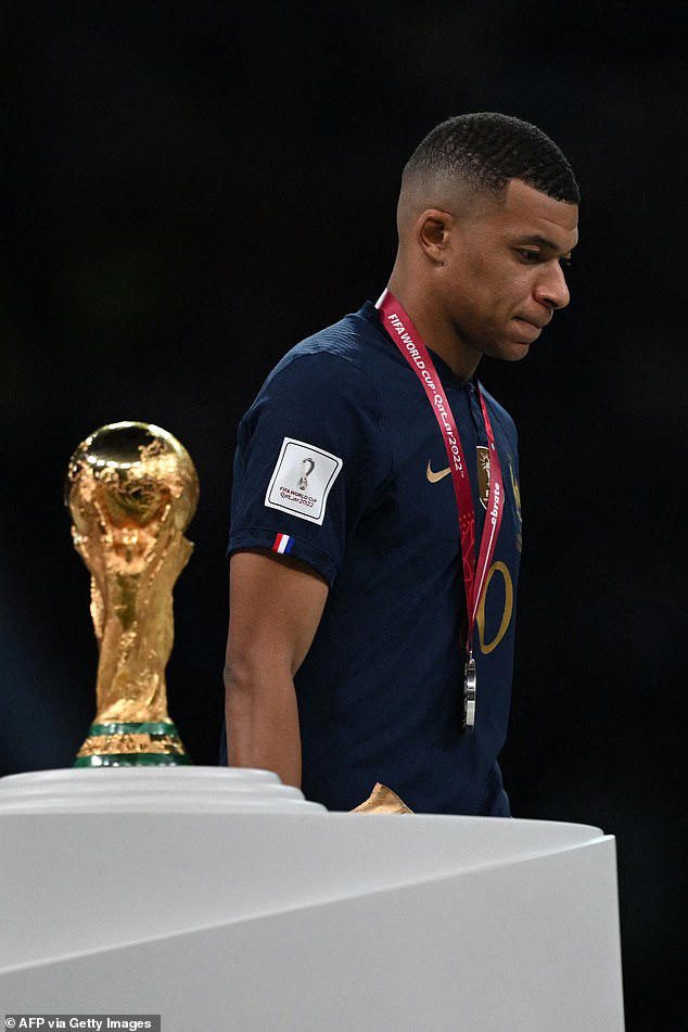 France lost the Qatar 2022 World Cup final, and lian Mbappe looks sad as he walks past the FIFA World Cup Trophy during the trophy ceremony.