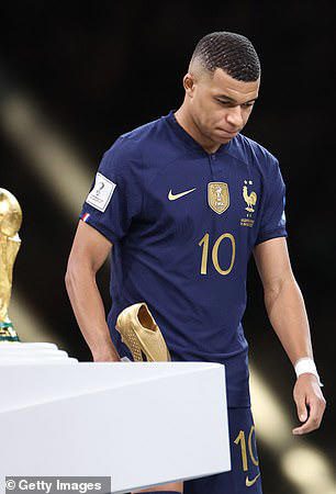 Kylian Mbappe of France lowers his head as he walks by the FIFA World Cup Trophy.