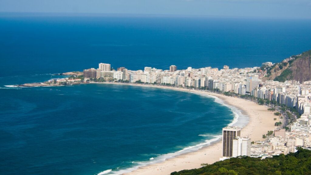 A vibrant view of Copacabana Beach in Rio de Janeiro, featuring its iconic promenade, golden sands, and lively beachgoers.