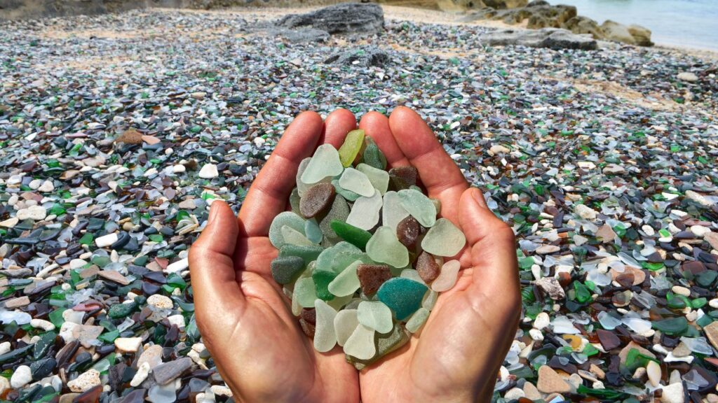 A colorful view of Glass Beach in Fort Bragg, California, showcasing smooth sea glass pieces scattered across the pebbly shore.