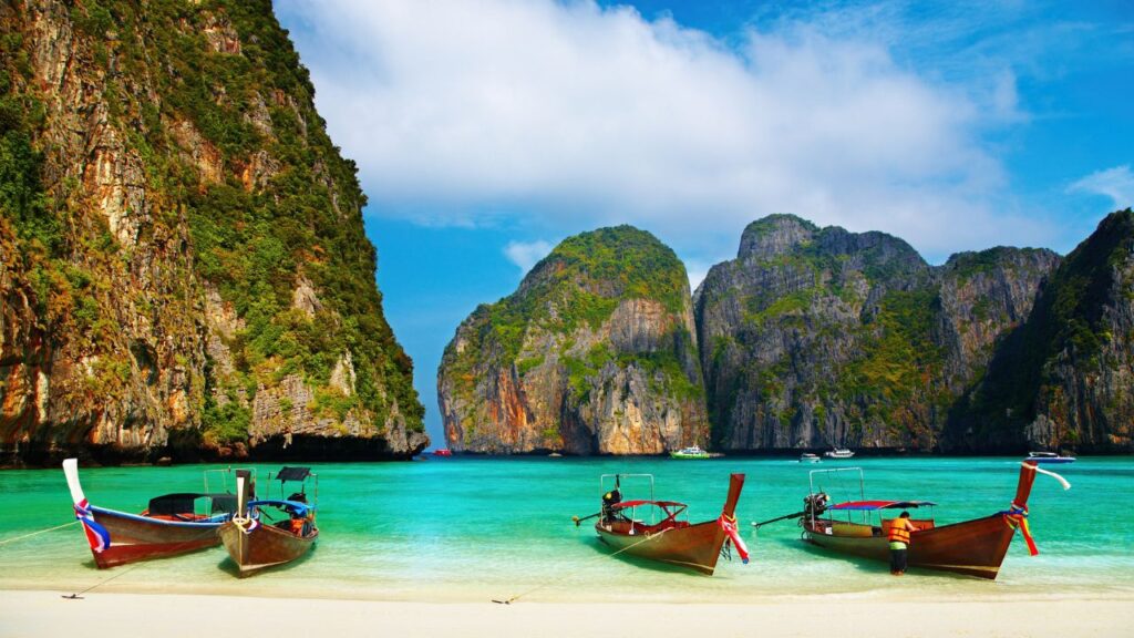 A breathtaking view of Maya Bay in Thailand, featuring its turquoise waters, towering limestone cliffs, and lush greenery.