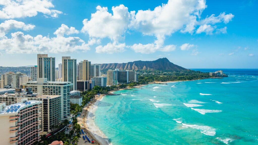 A vibrant view of Waikiki Beach in Hawaii, featuring surfers riding the waves and the iconic Diamond Head crater in the background.